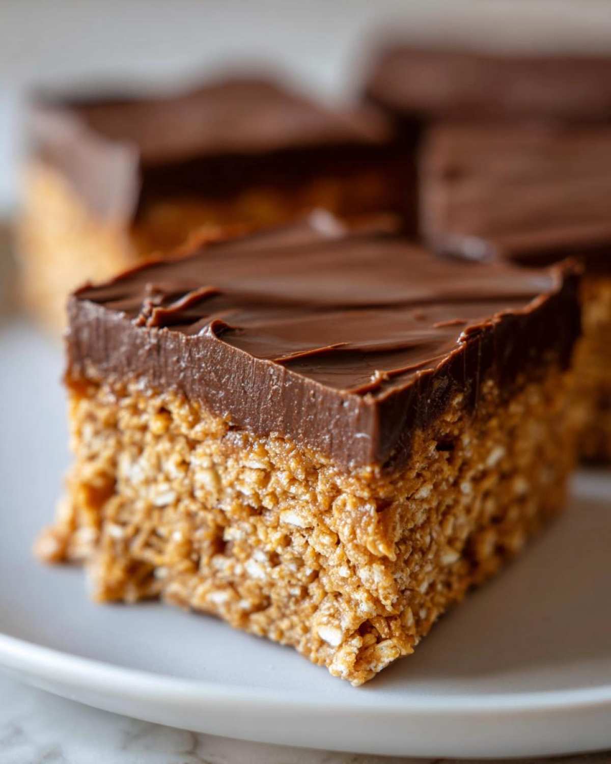A square serving of No-Bake Chocolate Peanut Butter Oat Bars showing the textured oat base and thick chocolate topping.