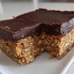 A square serving of No-Bake Chocolate Peanut Butter Oat Bars showing the thick oat base and chocolate topping.