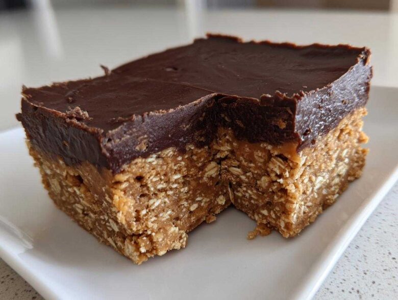 A square serving of No-Bake Chocolate Peanut Butter Oat Bars showing the thick oat base and chocolate topping.