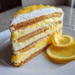 A tall slice of No-Bake Lemon Icebox Cake showing layers of graham crackers, lemon filling, and whipped cream, garnished with lemon slices.