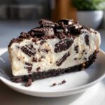 A generous slice of No-Bake Oreo Cheesecake showing creamy filling mixed with chocolate cookie pieces.