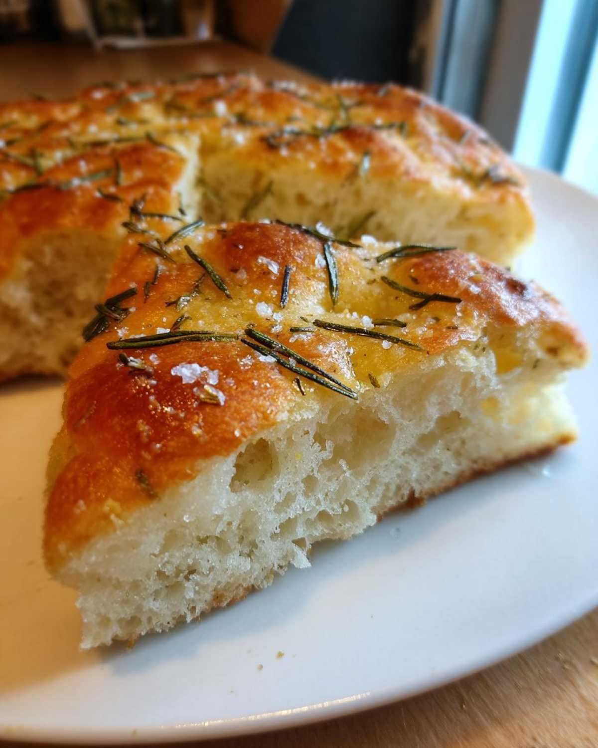 Close-up of a fluffy slice of No-Knead Skillet Focaccia with Rosemary, topped with sea salt.