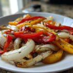 Close-up of colorful sautéed peppers and onions seasoned with herbs, ready for One-Pan Chicken Fajitas.