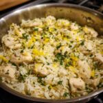 Close-up of One-Pot Chicken and Rice with Lemon and Herbs, featuring white rice, cubed chicken, and bright yellow lemon zest and green herbs.