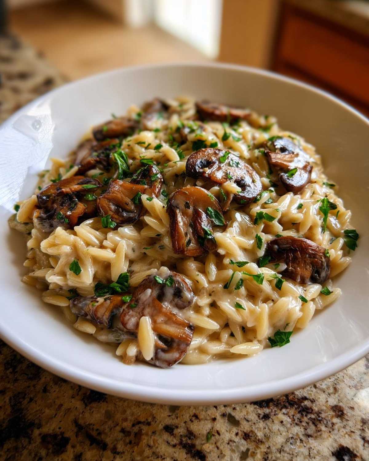 A close-up of a serving of One-Pot Creamy Mushroom Orzo topped with sautéed mushrooms and fresh parsley.