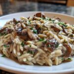 Close-up of a serving of One-Pot Creamy Mushroom Orzo garnished with fresh parsley.