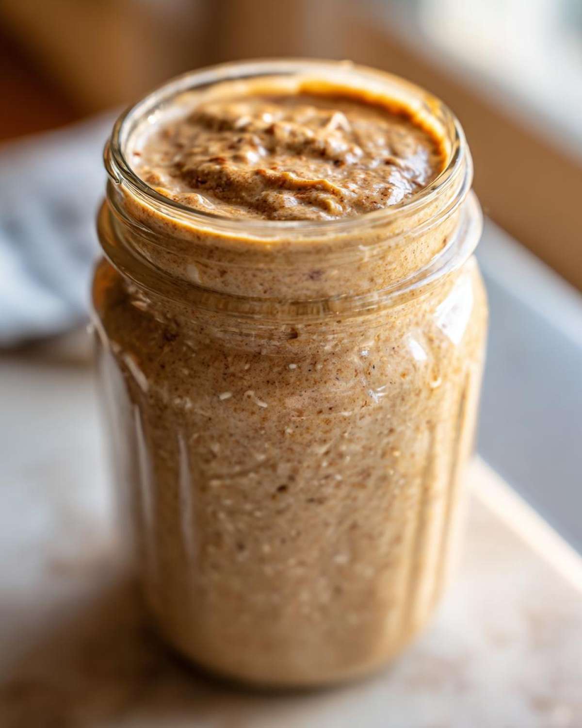 Close-up of a glass jar filled with the creamy, textured peanut butter mixture for High-Protein Peanut Butter Overnight Oats.