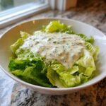 A bowl of crisp romaine lettuce generously topped with creamy Copycat Olive Garden Salad Dressing.