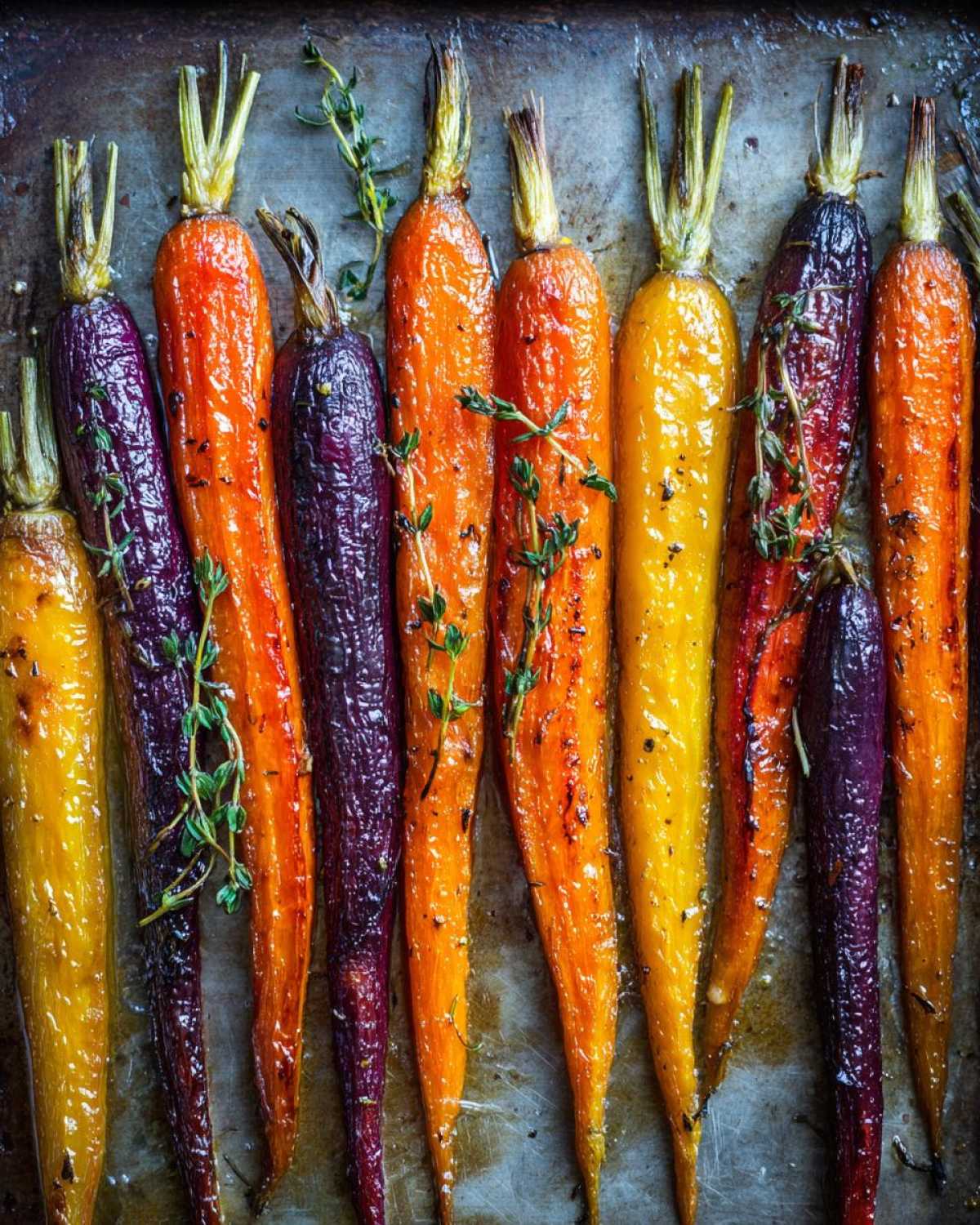 Close-up of vibrant Sheet Pan Roasted Rainbow Carrots with Honey and fresh thyme on a baking sheet.