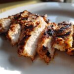 Close-up of sliced, grilled Copycat Chipotle Chicken showing char marks and juicy interior on a white plate.