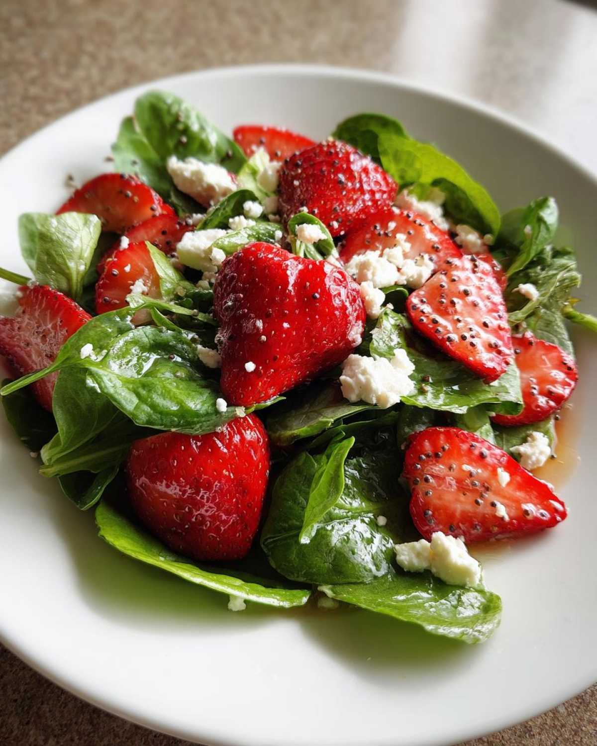 Close-up of a vibrant Spring Mix Salad with Strawberries and Goat Cheese served on a white plate.