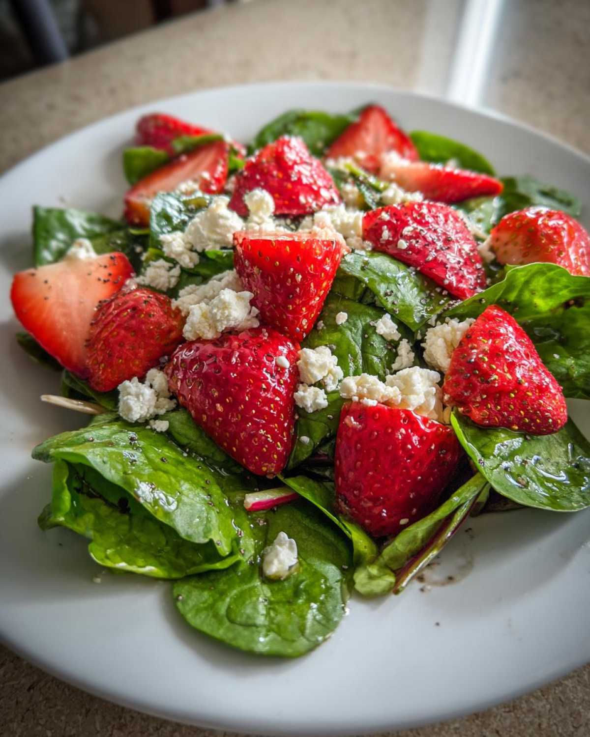 Close-up of a vibrant Spring Mix Salad with Strawberries and Goat Cheese on a white plate.