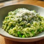Close-up of creamy Spring Pea and Mint Risotto topped with grated Parmesan cheese in a light bowl.