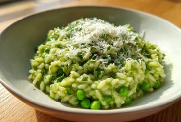 Close-up of creamy Spring Pea and Mint Risotto topped with grated Parmesan cheese in a light bowl.
