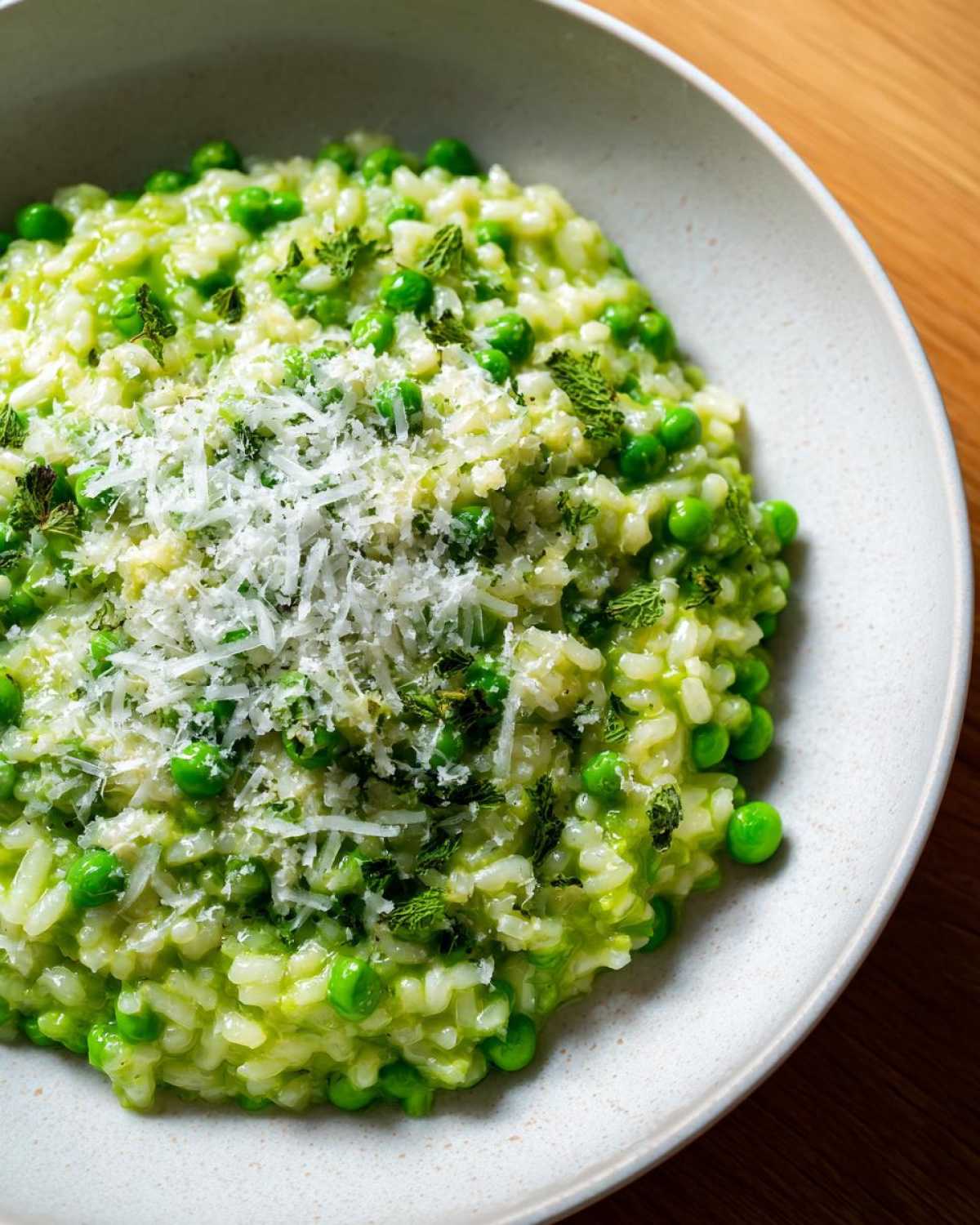 Creamy Spring Pea and Mint Risotto topped with grated Parmesan cheese and fresh mint.