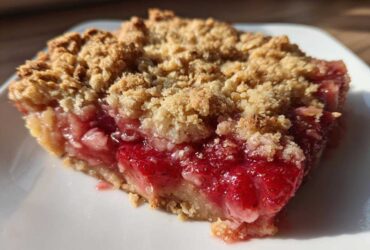 Close-up of a juicy slice of Strawberry Rhubarb Crisp showing the bright red fruit filling and crumbly topping.