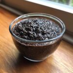 Close-up of rich Vegan Chocolate Chia Pudding with visible seeds in a clear glass bowl.
