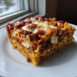 A generous square serving of Cheesy Baked Ziti with Ground Beef and Sauce on a white plate.