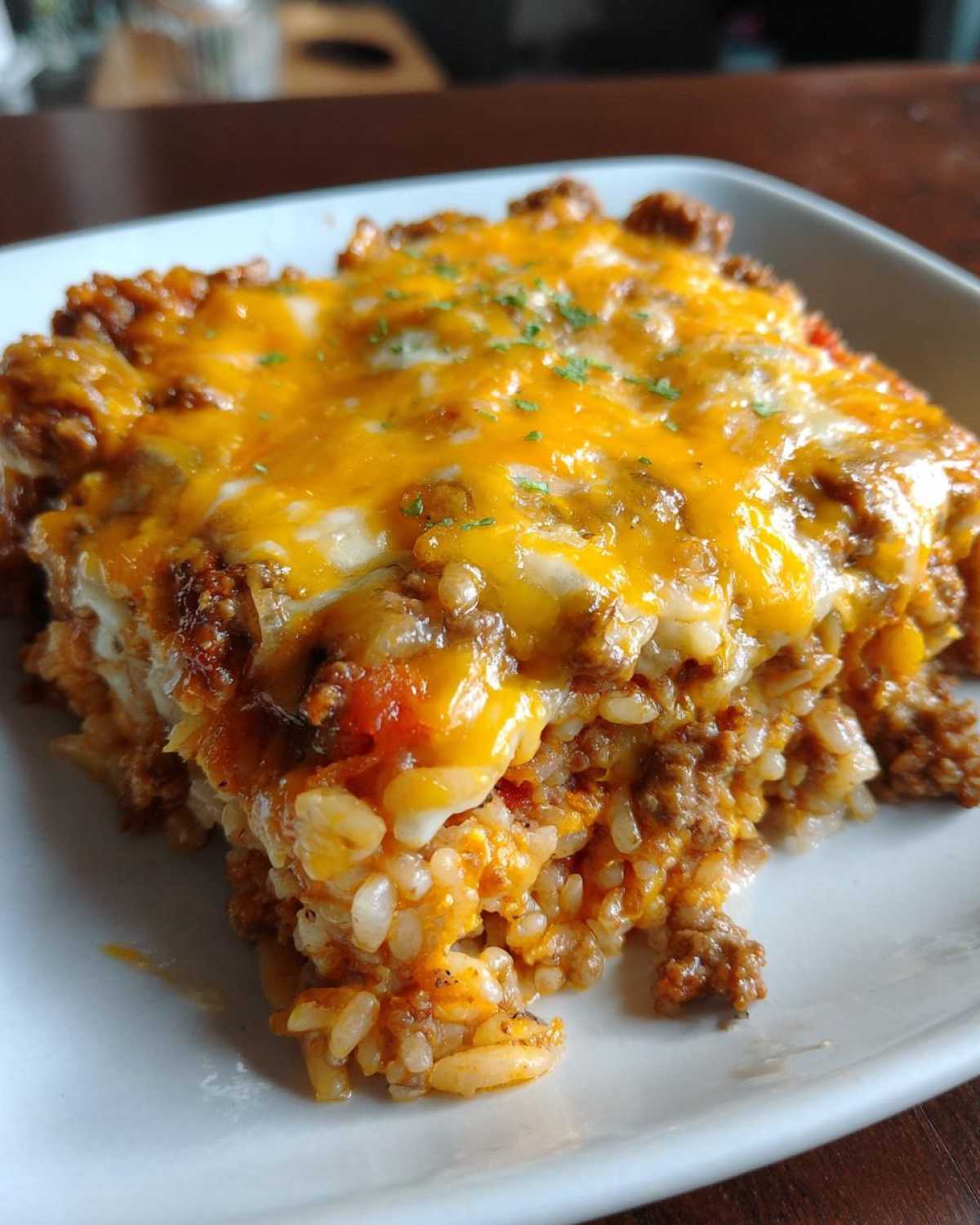 A close-up of a hearty serving of Cheesy Beef and Rice Casserole Comfort Dish topped with melted cheddar cheese.