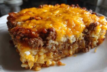 Close-up of a serving of Cheesy Beef and Rice Casserole Comfort Dish topped with melted cheddar cheese.