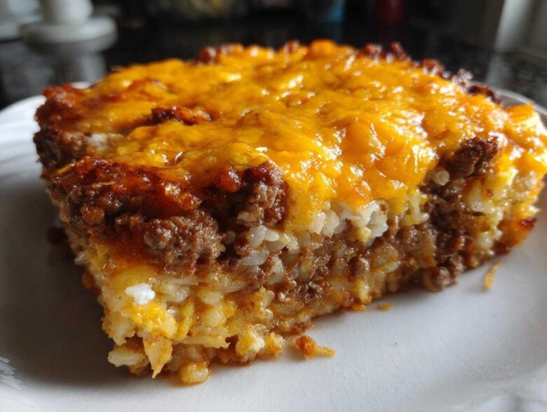 Close-up of a serving of Cheesy Beef and Rice Casserole Comfort Dish topped with melted cheddar cheese.
