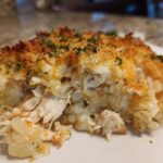 A close-up serving of Cheesy Chicken and Rice Bake showing shredded chicken, creamy rice, and a crispy, golden topping.