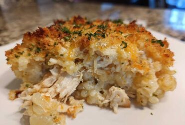 A close-up serving of Cheesy Chicken and Rice Bake showing shredded chicken, creamy rice, and a crispy, golden topping.