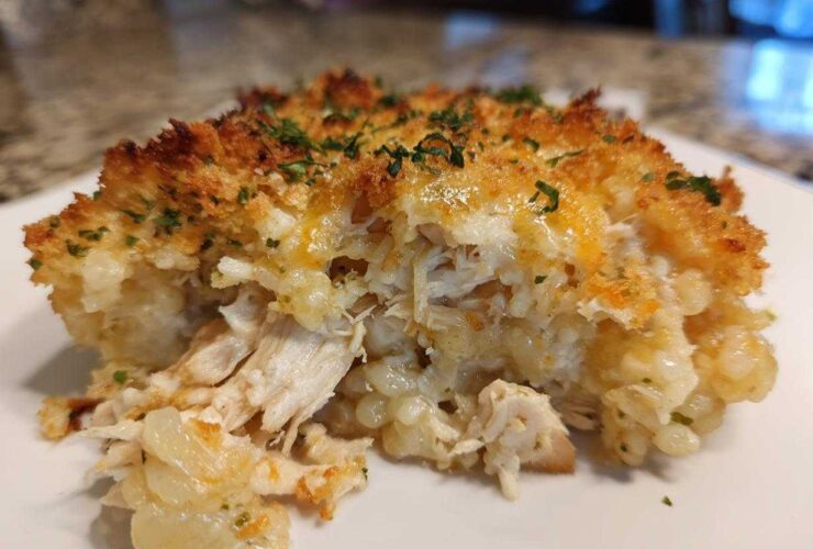 A close-up serving of Cheesy Chicken and Rice Bake showing shredded chicken, creamy rice, and a crispy, golden topping.