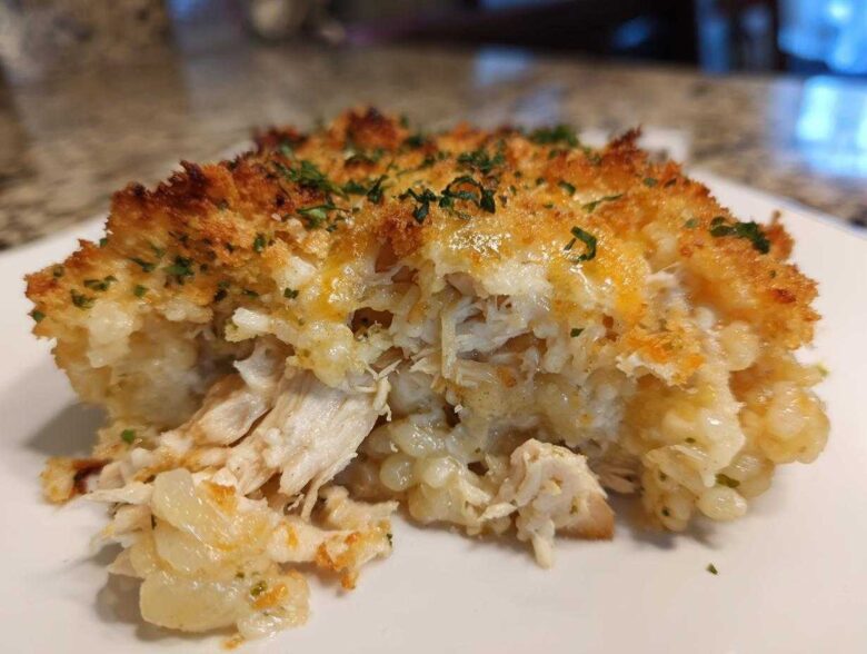 A close-up serving of Cheesy Chicken and Rice Bake showing shredded chicken, creamy rice, and a crispy, golden topping.