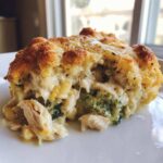 A close-up view of a serving of Cheesy Chicken and Broccoli Bake Comfort Dish, showing melted cheese, shredded chicken, and broccoli florets.