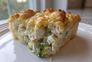 A close-up of a square slice of Cheesy Chicken and Broccoli Bake Comfort Dish with a golden, cheesy crust.