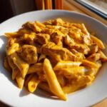 Close-up of a white bowl filled with Cheesy Chicken Pasta with Creamy Sauce, featuring penne pasta and chunks of seasoned chicken.