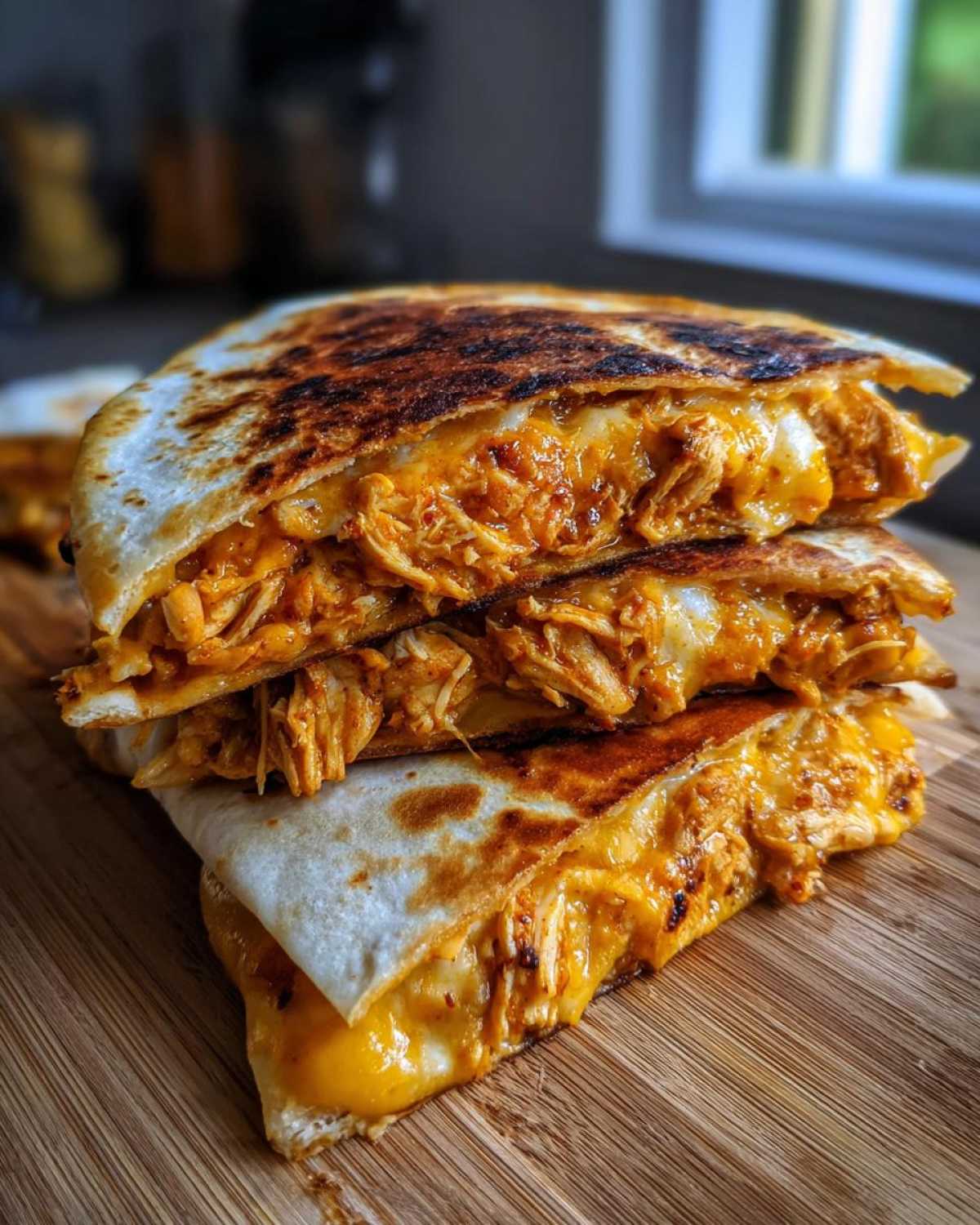 Three stacked, grilled wedges of Cheesy Chicken Quesadilla with Creamy Filling oozing melted cheese.