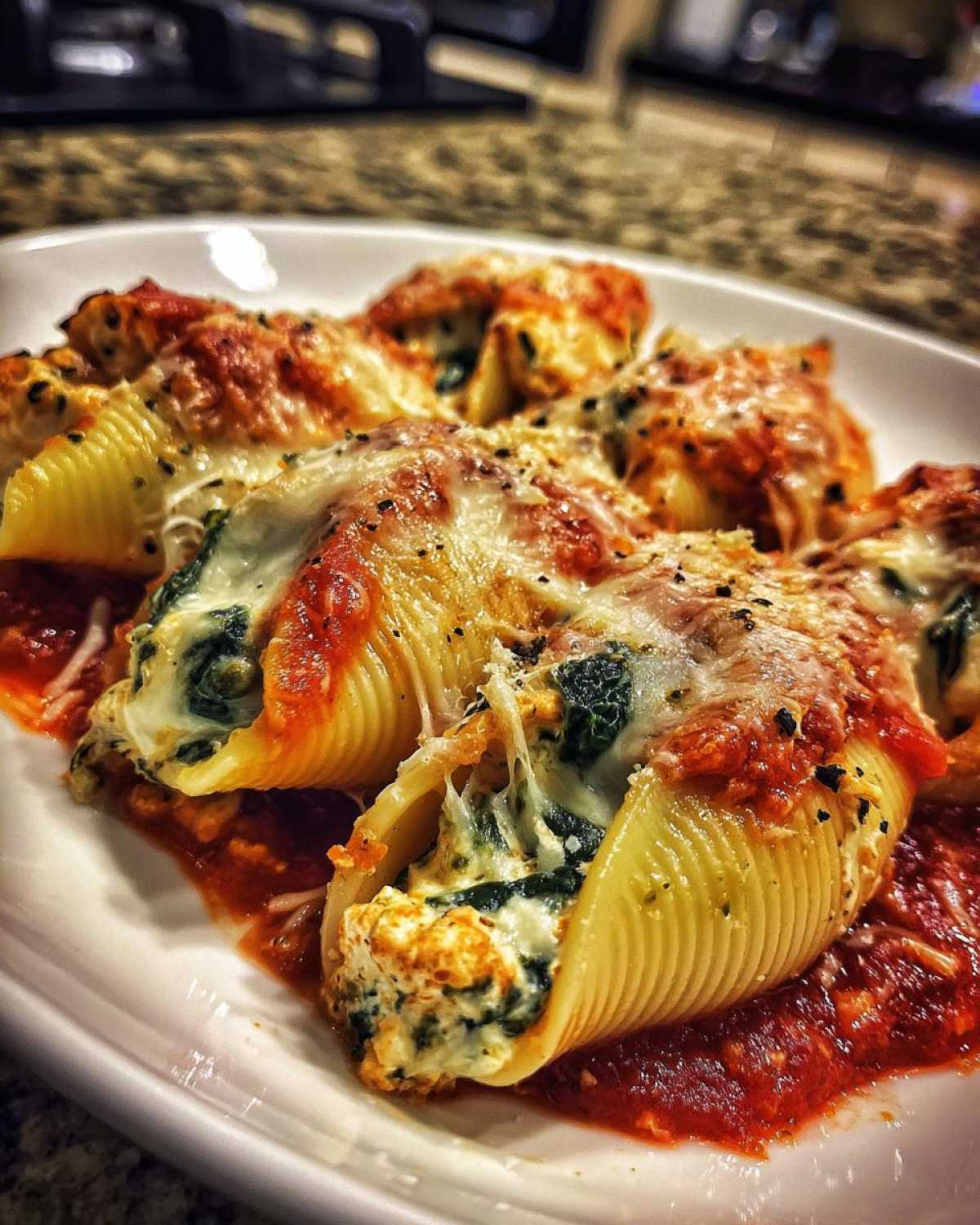 Close-up of baked Cheesy Chicken Stuffed Shells with Spinach, covered in melted cheese and marinara sauce.