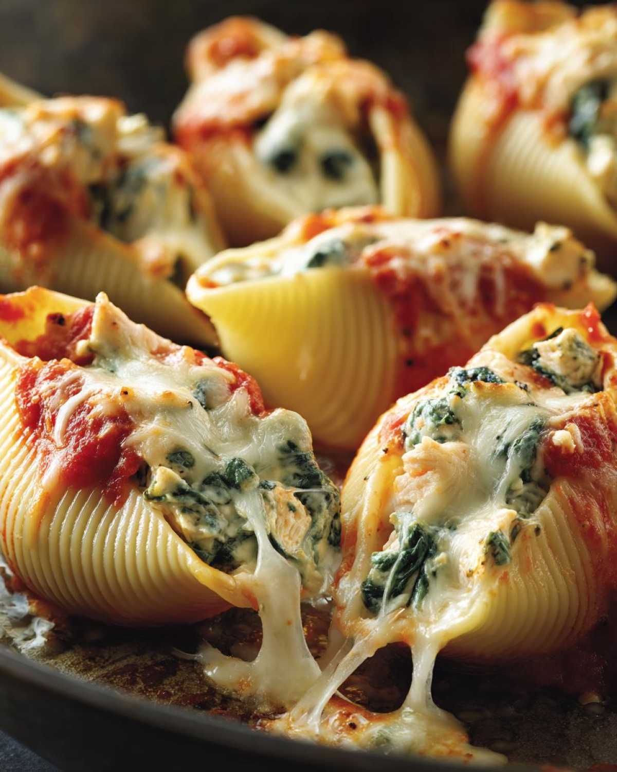Close-up of Cheesy Chicken Stuffed Shells with Spinach, showing melted cheese stretching between two shells.