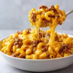A spoonful of Cheesy Ground Beef Pasta with Creamy Sauce being lifted, showing long, gooey cheese pulls.