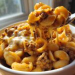 Close-up of Cheesy Ground Beef Pasta being lifted by a fork, showing long cheese pulls.