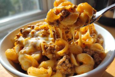 Close-up of Cheesy Ground Beef Pasta being lifted by a fork, showing long cheese pulls.