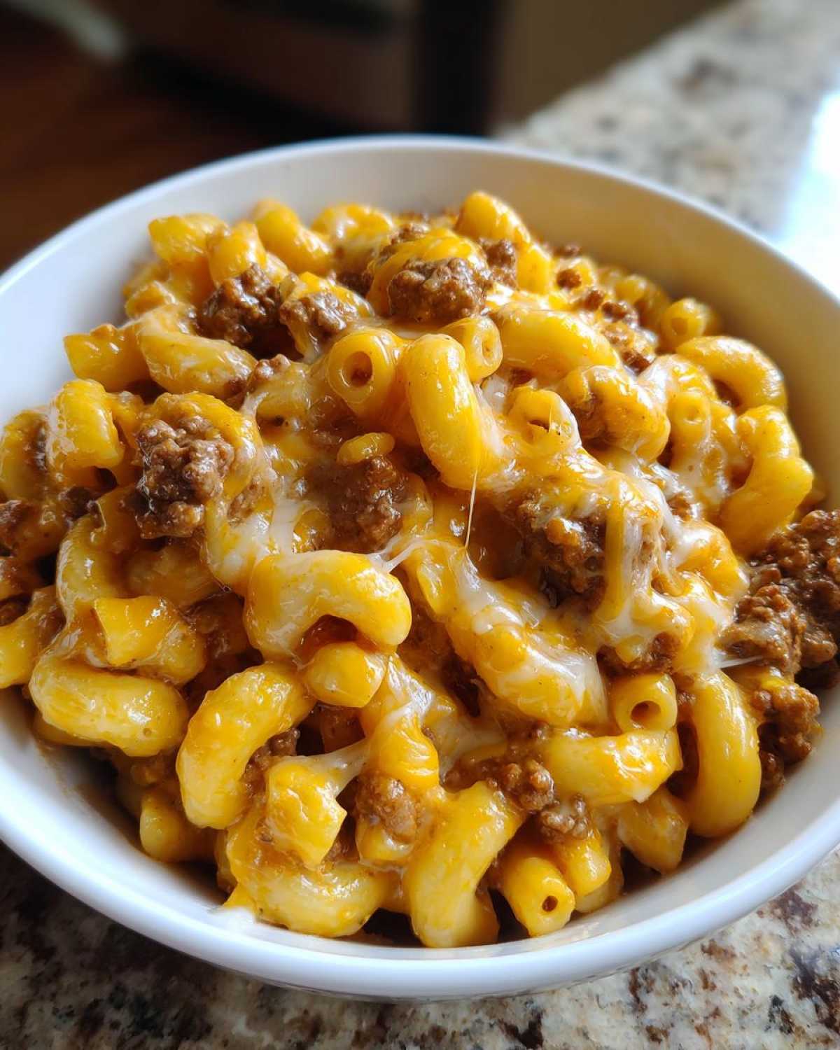 A close-up of Cheesy Ground Beef Pasta with macaroni noodles, ground beef, and melted cheddar and mozzarella cheese.