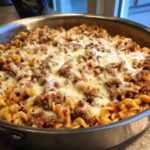 Close-up of a Cheesy Ground Beef Pasta Skillet topped with melted mozzarella cheese in a metal pan.