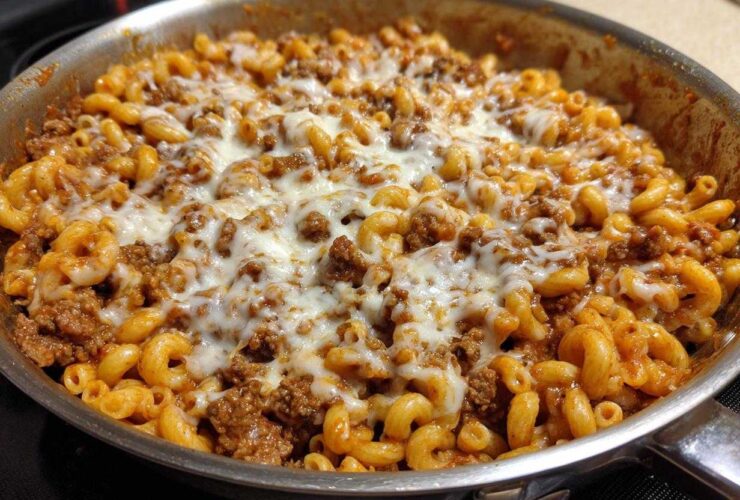 Close-up of Cheesy Ground Beef Pasta Skillet topped with melted mozzarella cheese in a stainless steel pan.