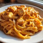A close-up of a generous serving of Creamy Cajun Chicken Pasta with fettuccine noodles and chunks of seasoned chicken.