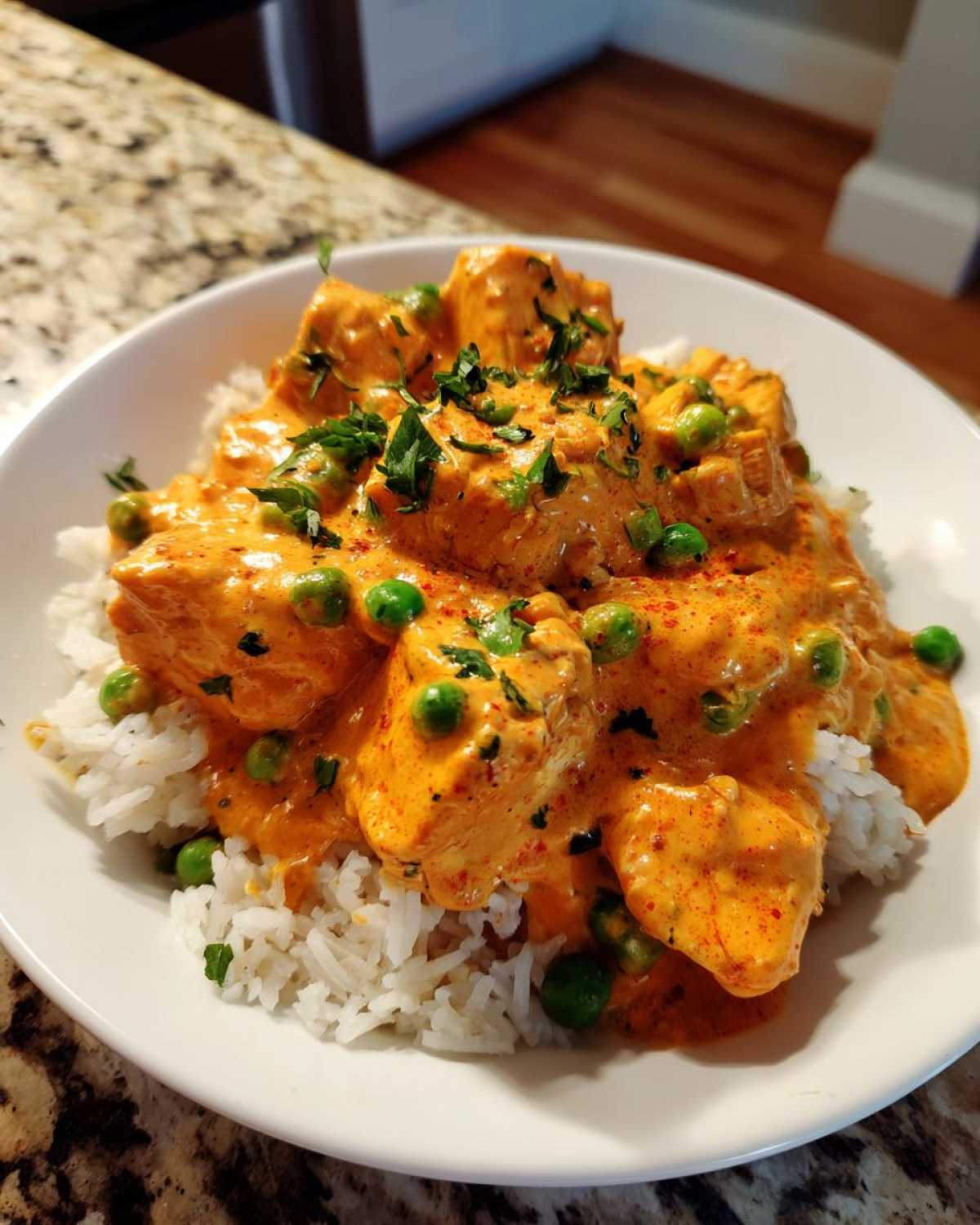 Close-up of Creamy Cajun Chicken Skillet with Rice, featuring orange sauce, chicken pieces, peas, and herbs.
