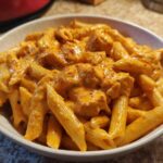 A close-up of a bowl filled with Creamy Cajun Pasta with Chicken and Spice, coated in a rich orange sauce.