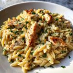 Close-up of a bowl filled with Creamy Garlic Parmesan Orzo with Chicken, topped with fresh parsley.