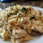 Close-up of a serving of Creamy Garlic Parmesan Orzo with Chicken, garnished with parsley.