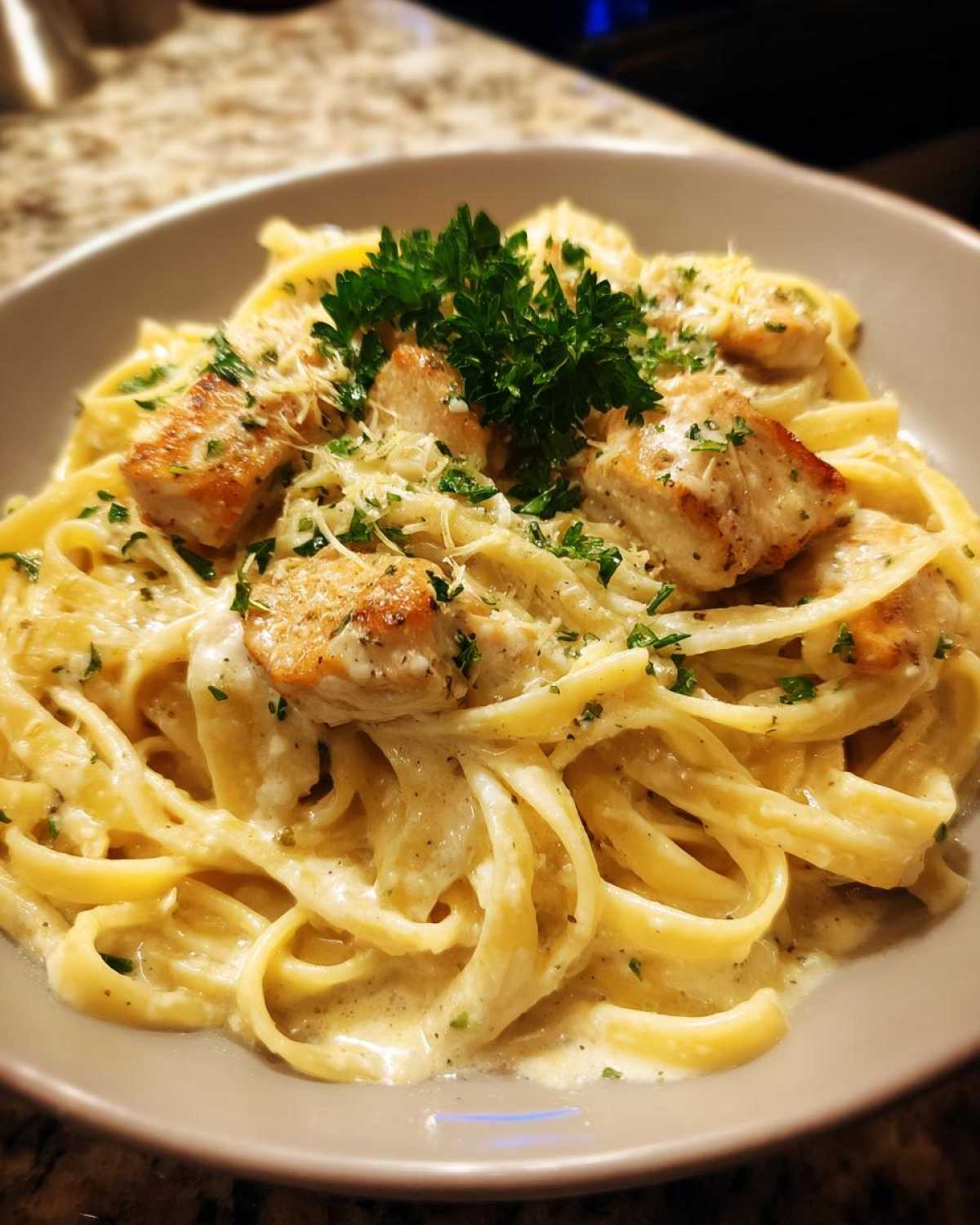 Close-up of creamy Honey Garlic Chicken Pasta with fettuccine, topped with seared chicken pieces and parsley.