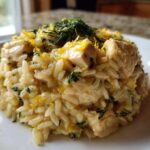 A mound of creamy Lemon Chicken Orzo with chunks of chicken, topped with lemon zest and fresh dill.