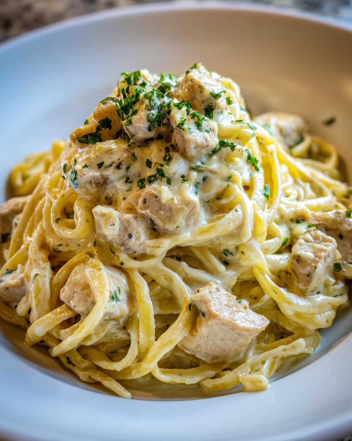 Close-up of Creamy Lemon Chicken Pasta featuring linguine noodles, diced chicken, and fresh parsley garnish.