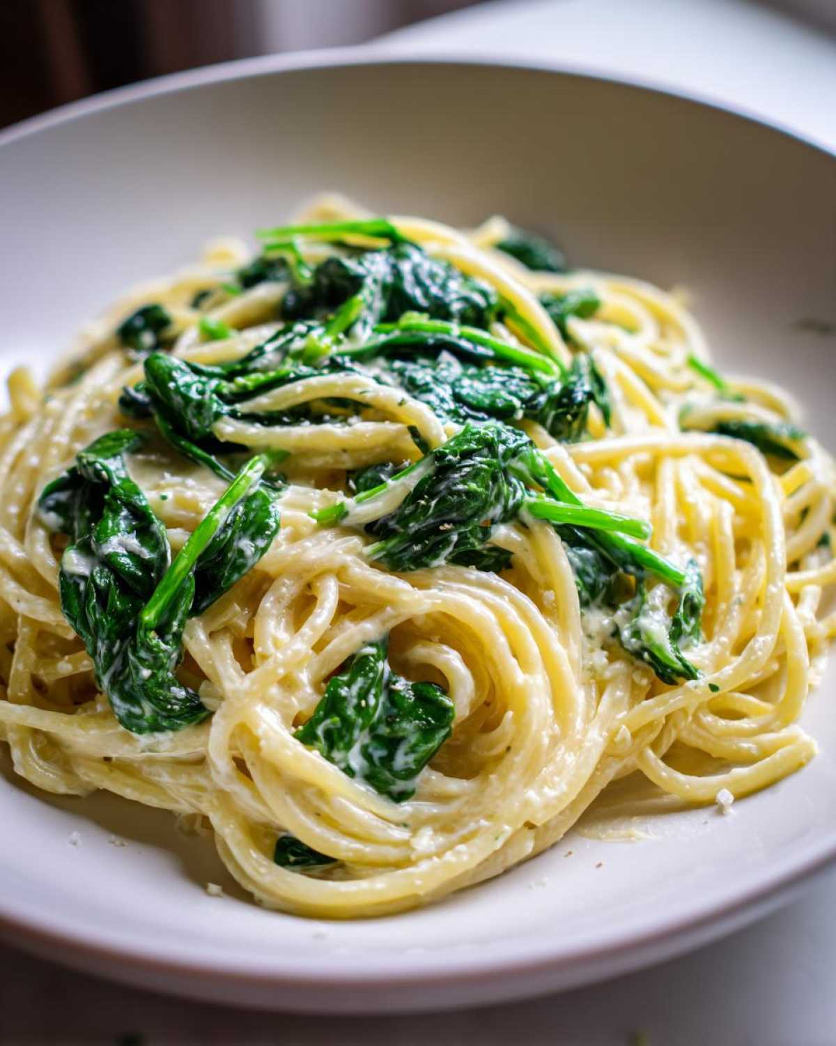 Close-up of spaghetti tossed in a creamy sauce with wilted spinach, representing Creamy Lemon Ricotta Pasta with Spinach.